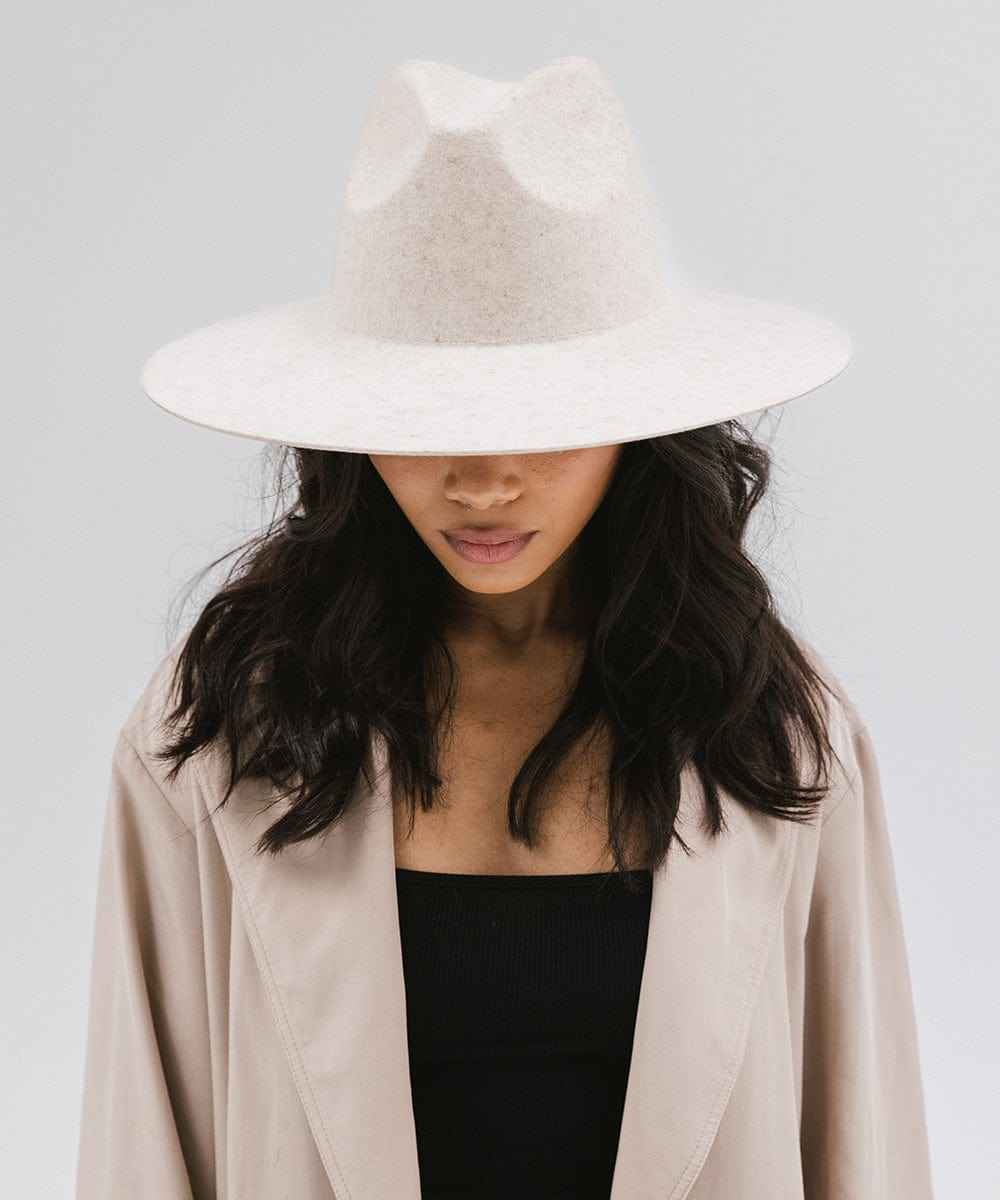 Person wearing a mix ivory colored wide brim hat and a beige coat against a plain background #color_mix ivory