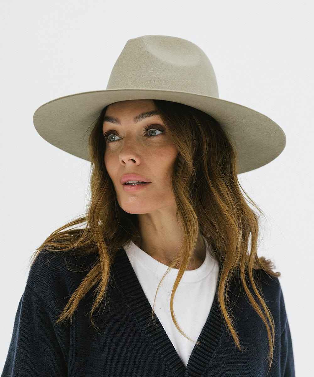 Woman wearing a sage colored wide brim hat and a blue sweater against a plain background #color_sage