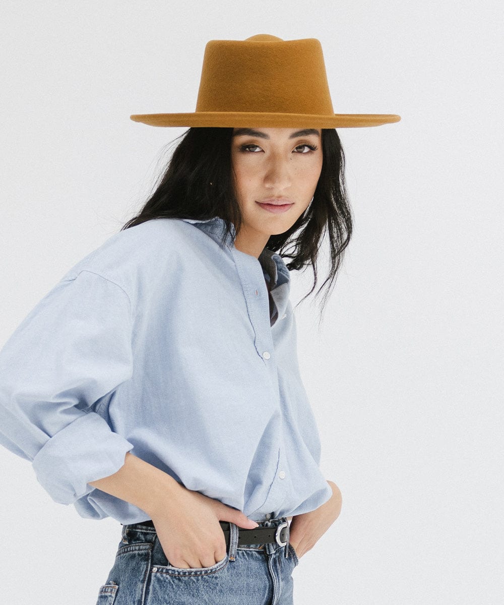 Woman wearing a cinnamon colored gambler hat and a blue shirt against a plain background #color_cinnamon