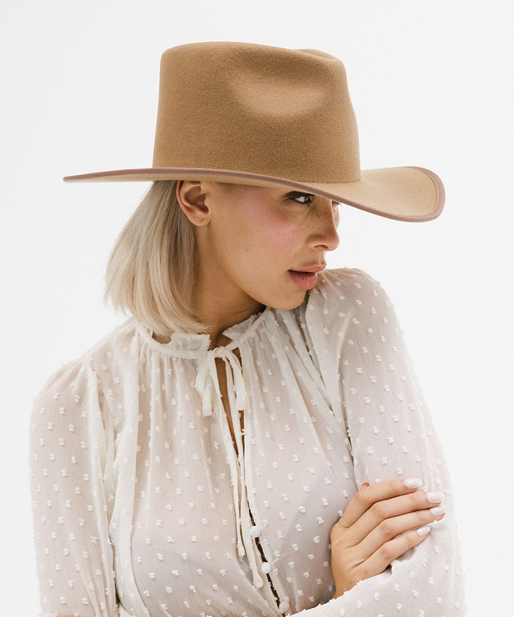 Woman wearing a brown felt western hat and a white top against a white background #color_brown