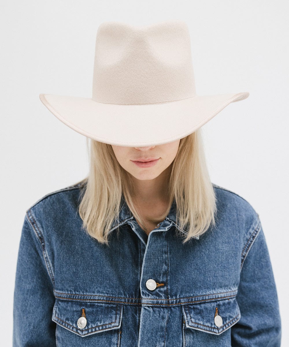 Person wearing a cream felt western hat and a denim shirt against a white background #color_cream
