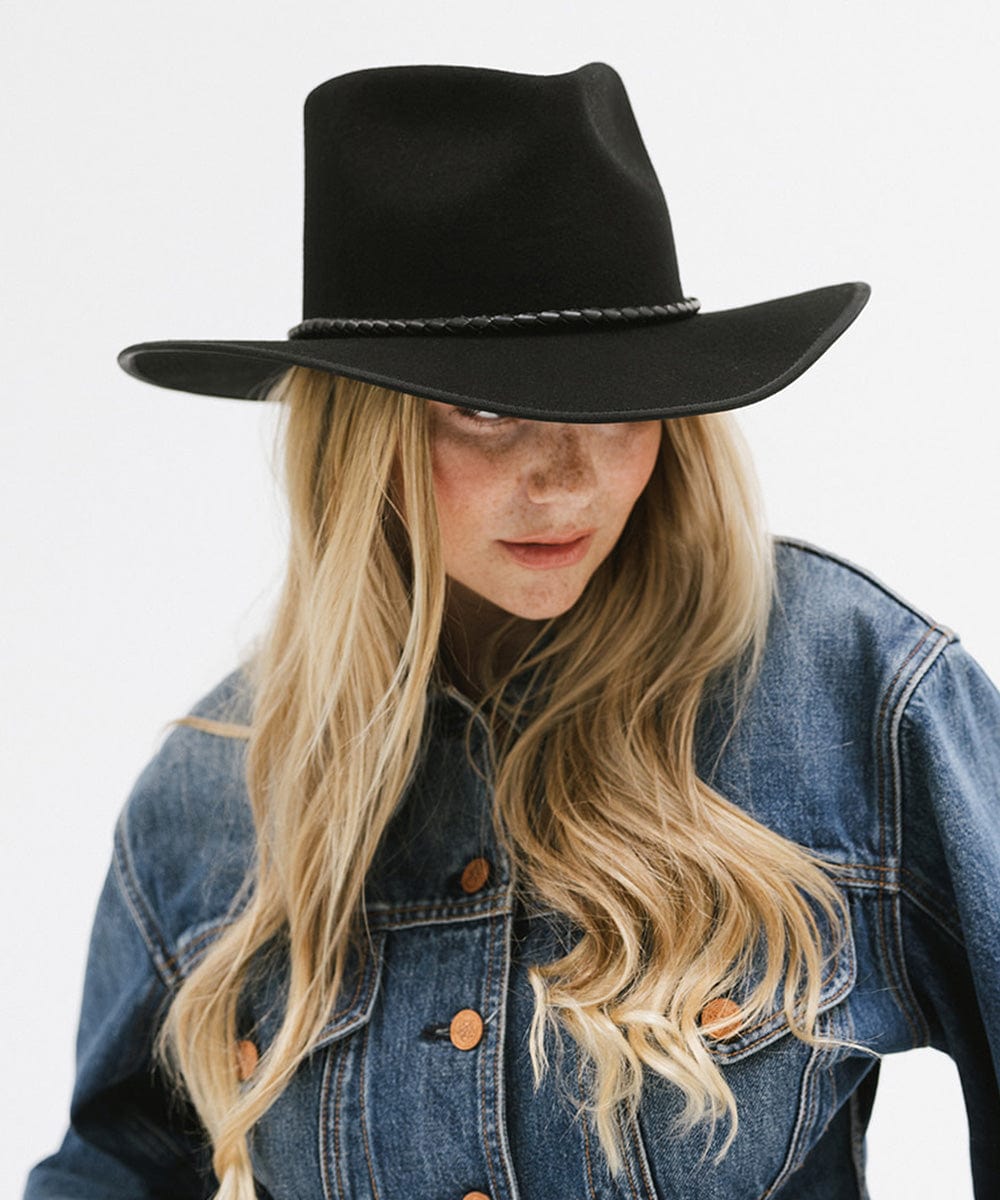Woman wearing a black felt western hat and a denim shirt against a white background #color_black