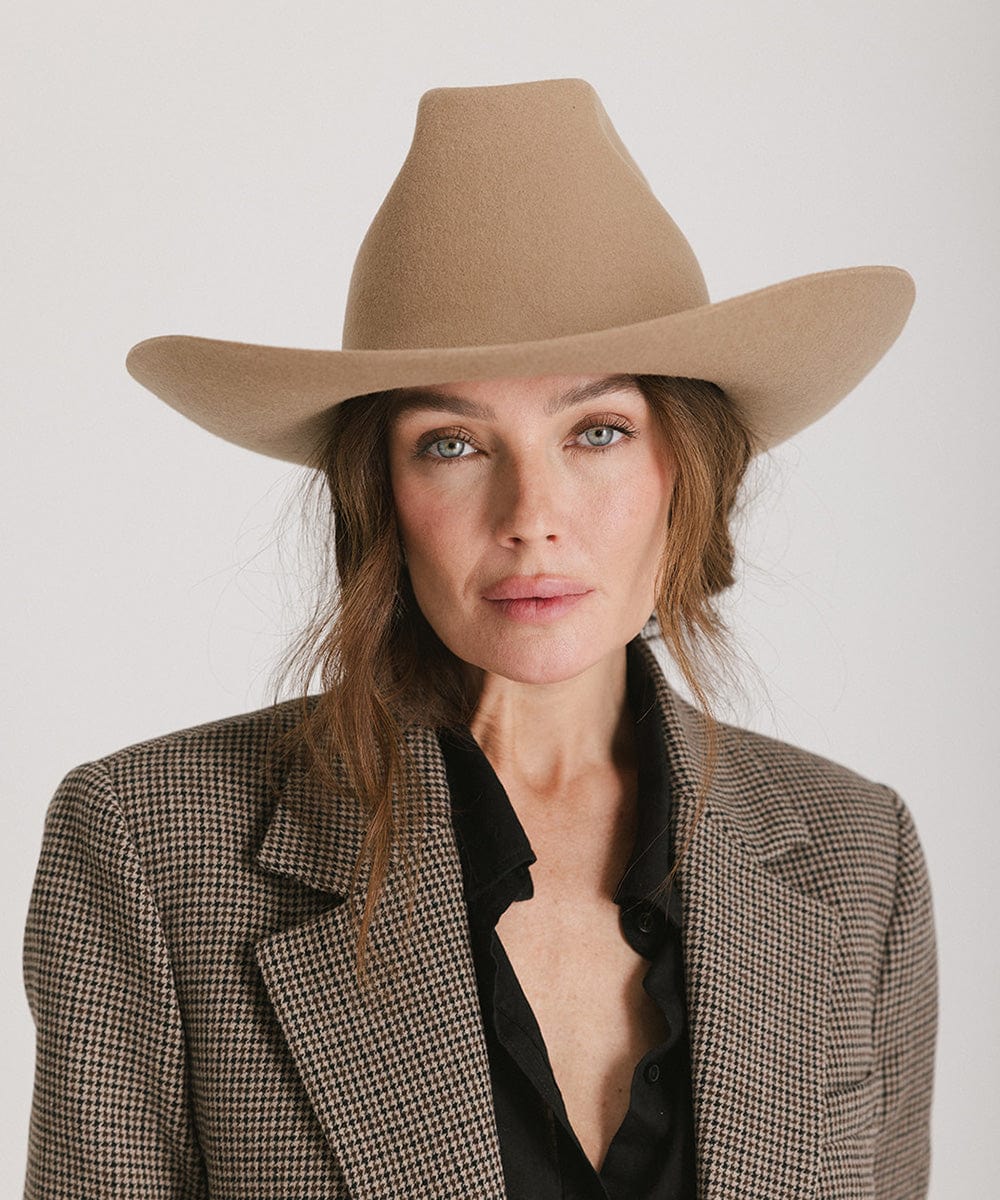 Woman wearing a brown cowboy hat and a blazer against a plain background #color_brown