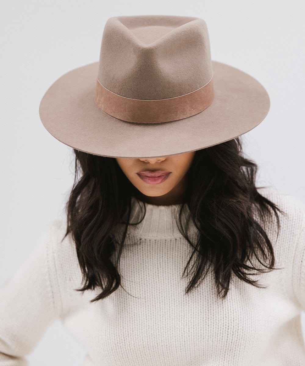 Person wearing a brown fedora hat against a light background #color_brown
