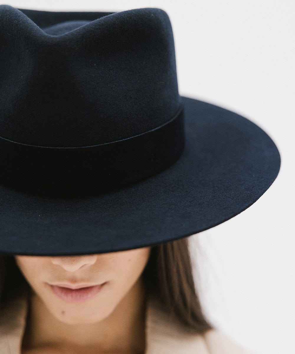 Navy fedora hat with a band worn by a person on a white background #color_navy