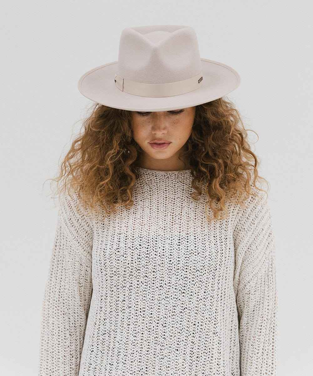 Woman wearing a white hat and knit sweater on a plain background #color_ivory