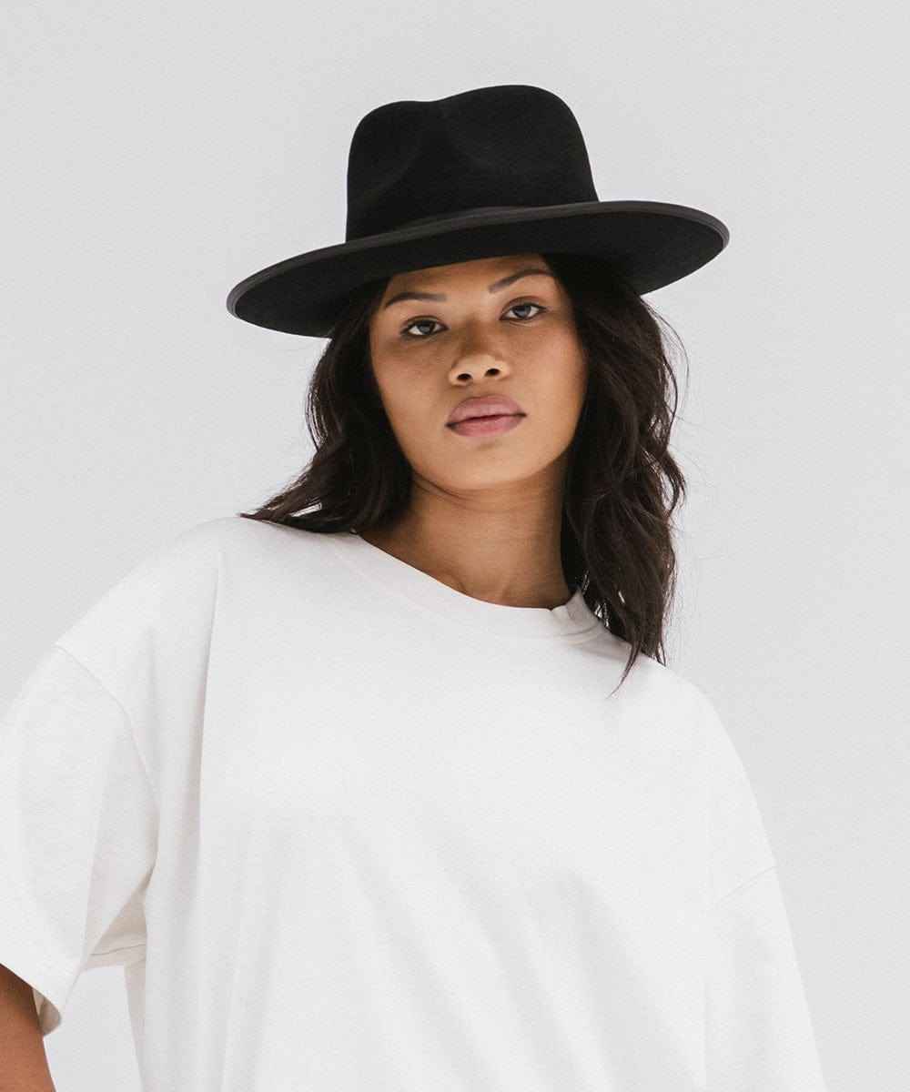 Woman wearing a black hat and white shirt against a plain background #color_black