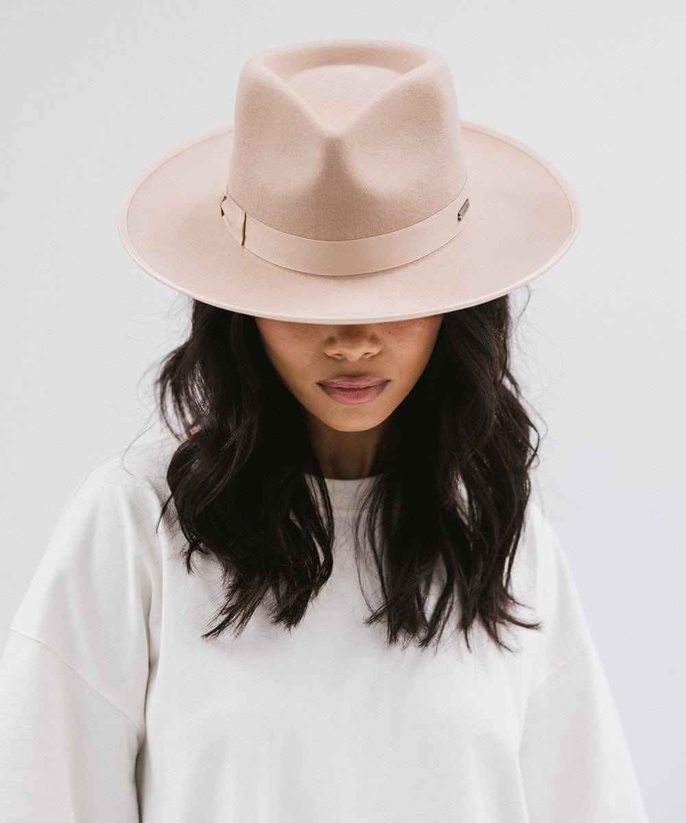 Woman wearing a nude fedora hat against a plain background #color_nude