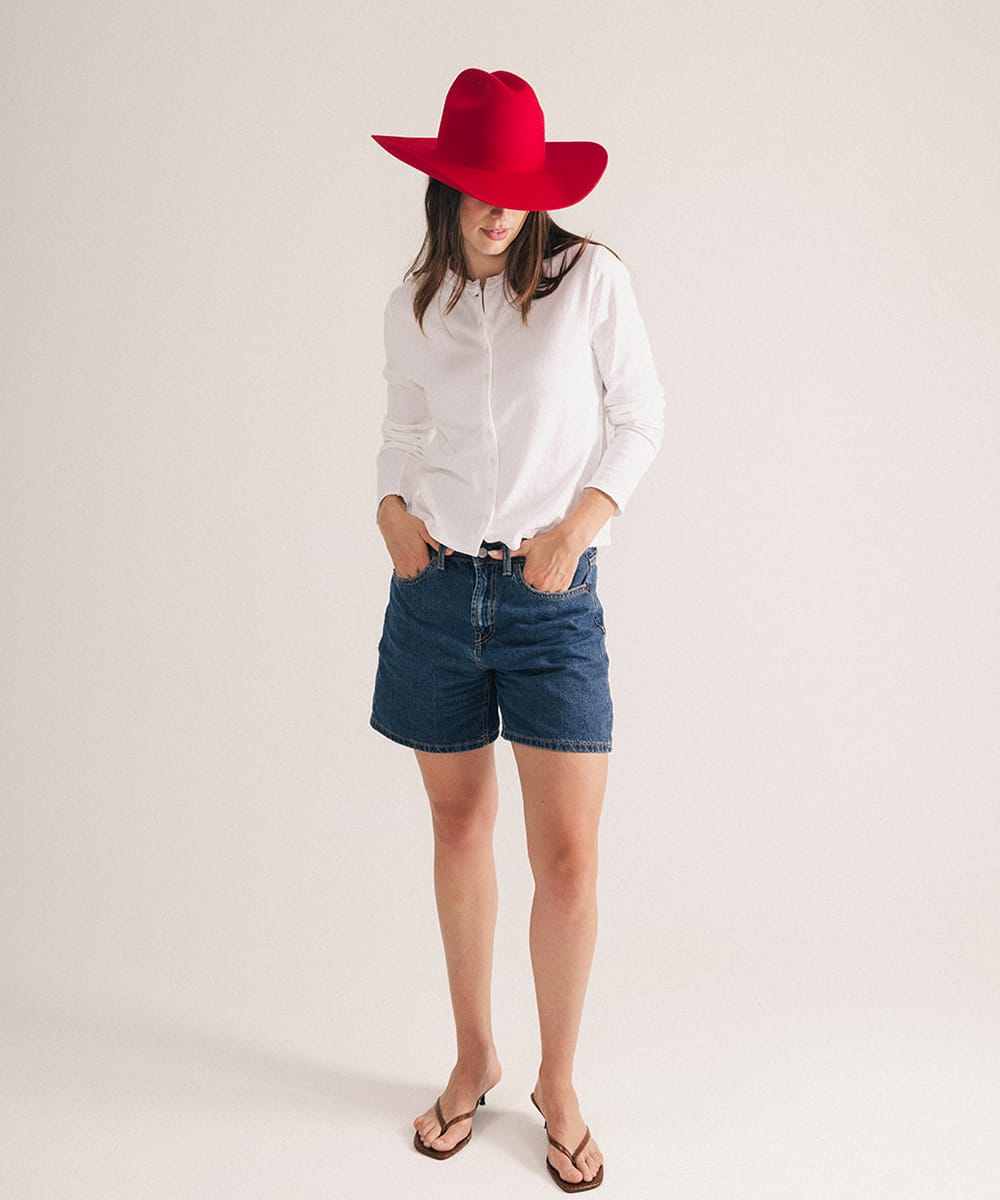 Woman wearing a red hat, white shirt, and denim shorts on a plain background #color_cherry red