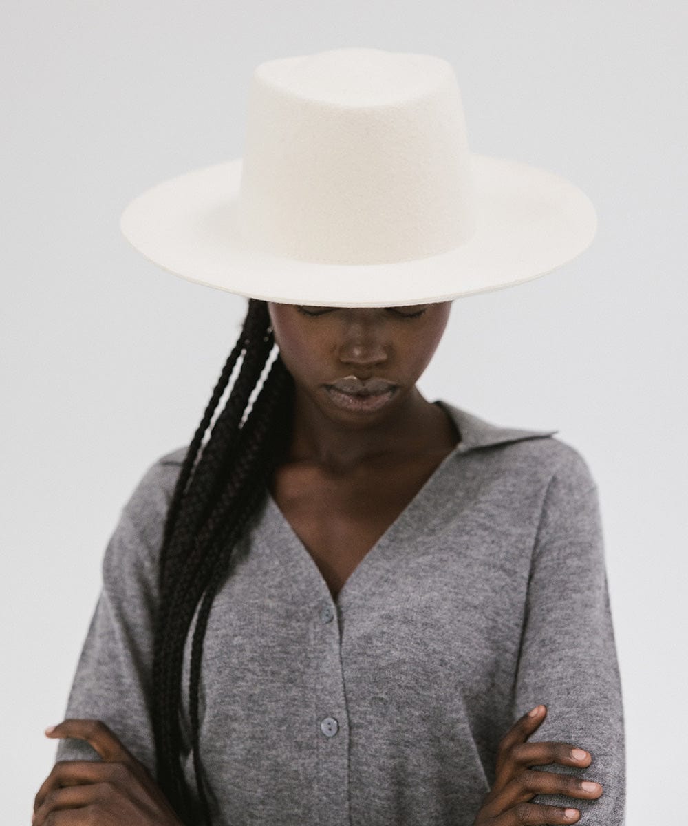 Woman wearing an off white gambler hat and a grey shirt against a plain background #color_off white