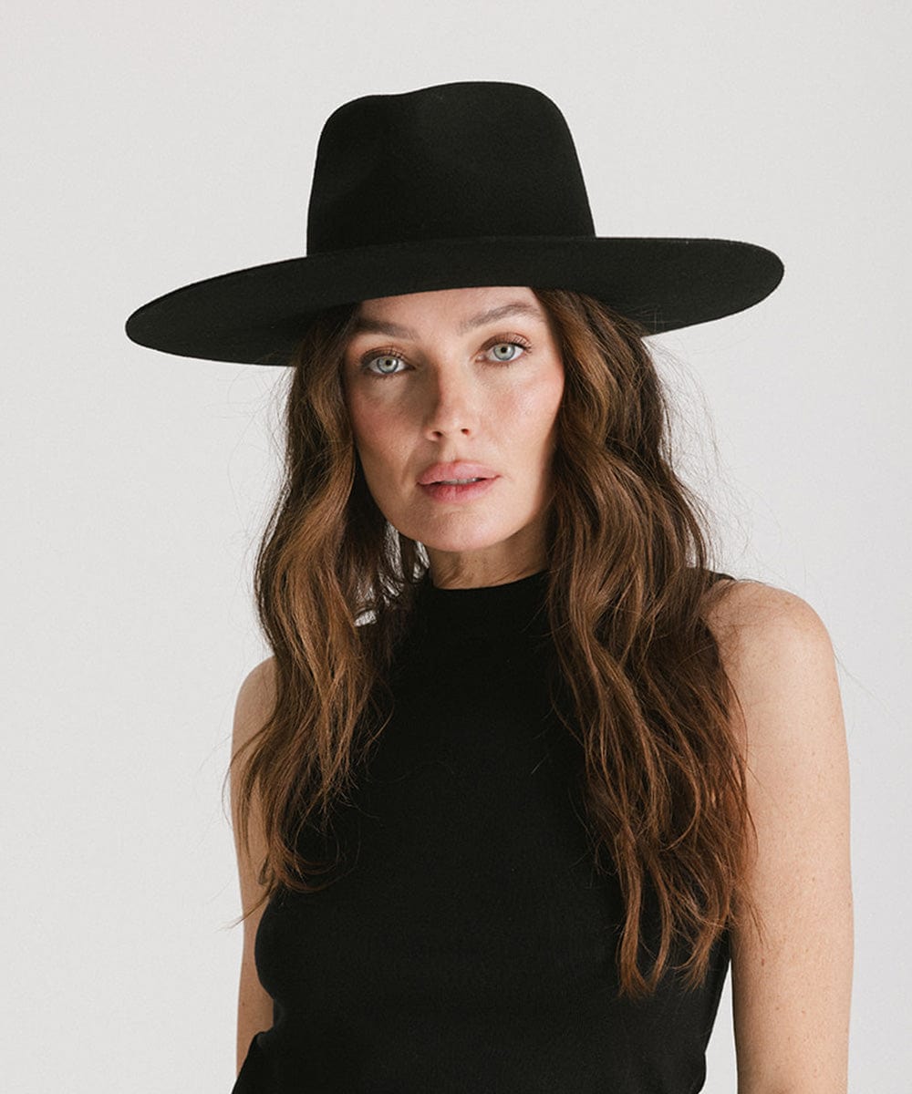 Woman wearing a black Wesley Wide Brim Fedora Hat and a black top against a plain background #color_black