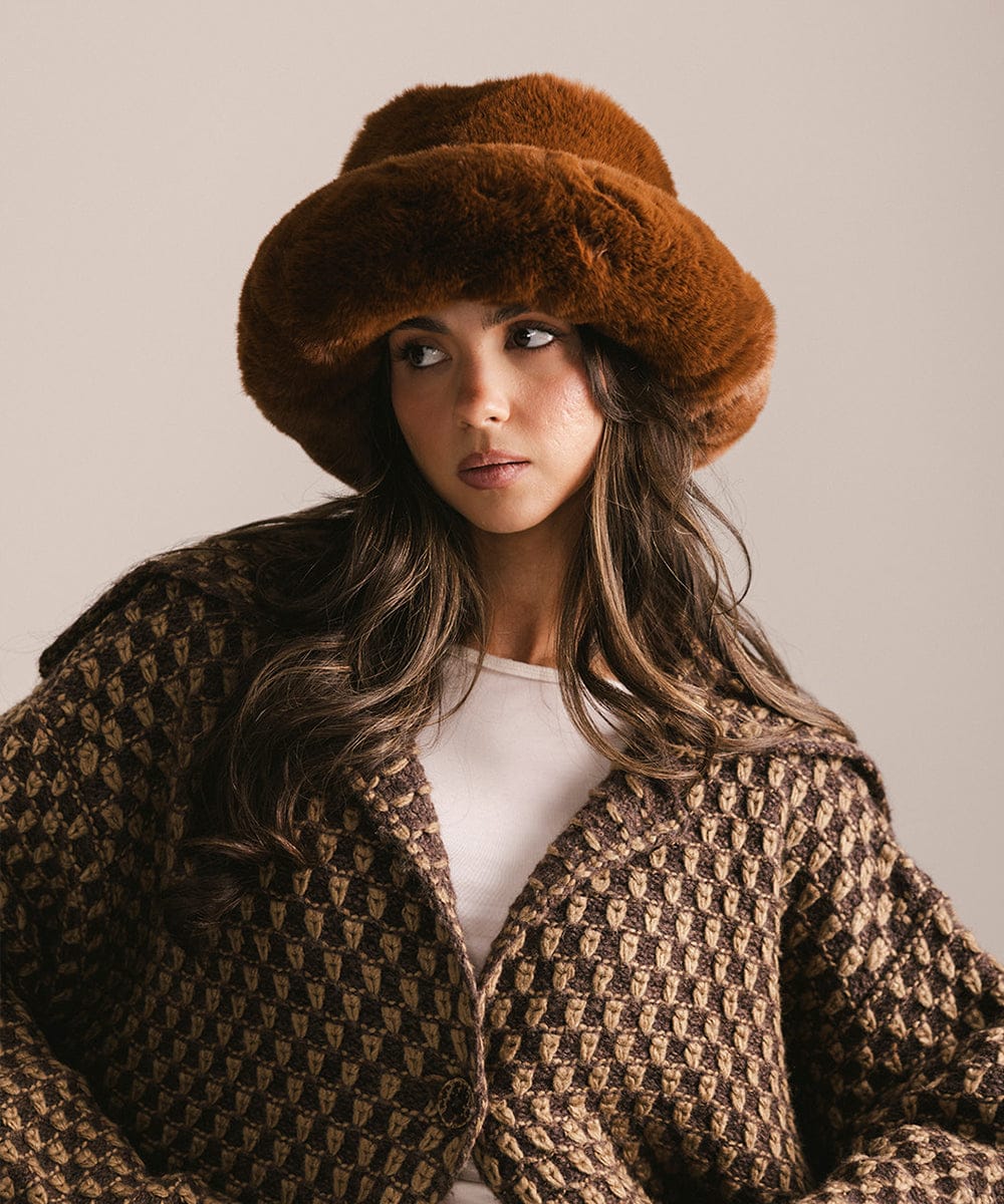 Woman wearing a brown fur hat and patterned coat against a neutral background #color_brown