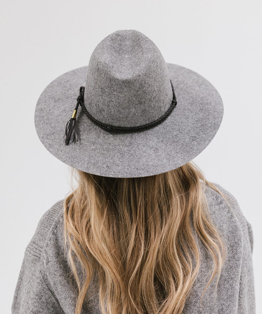 Person wearing grey cowboy hat with a black lasso braided hat band and a grey sweater against a plain background #color_black