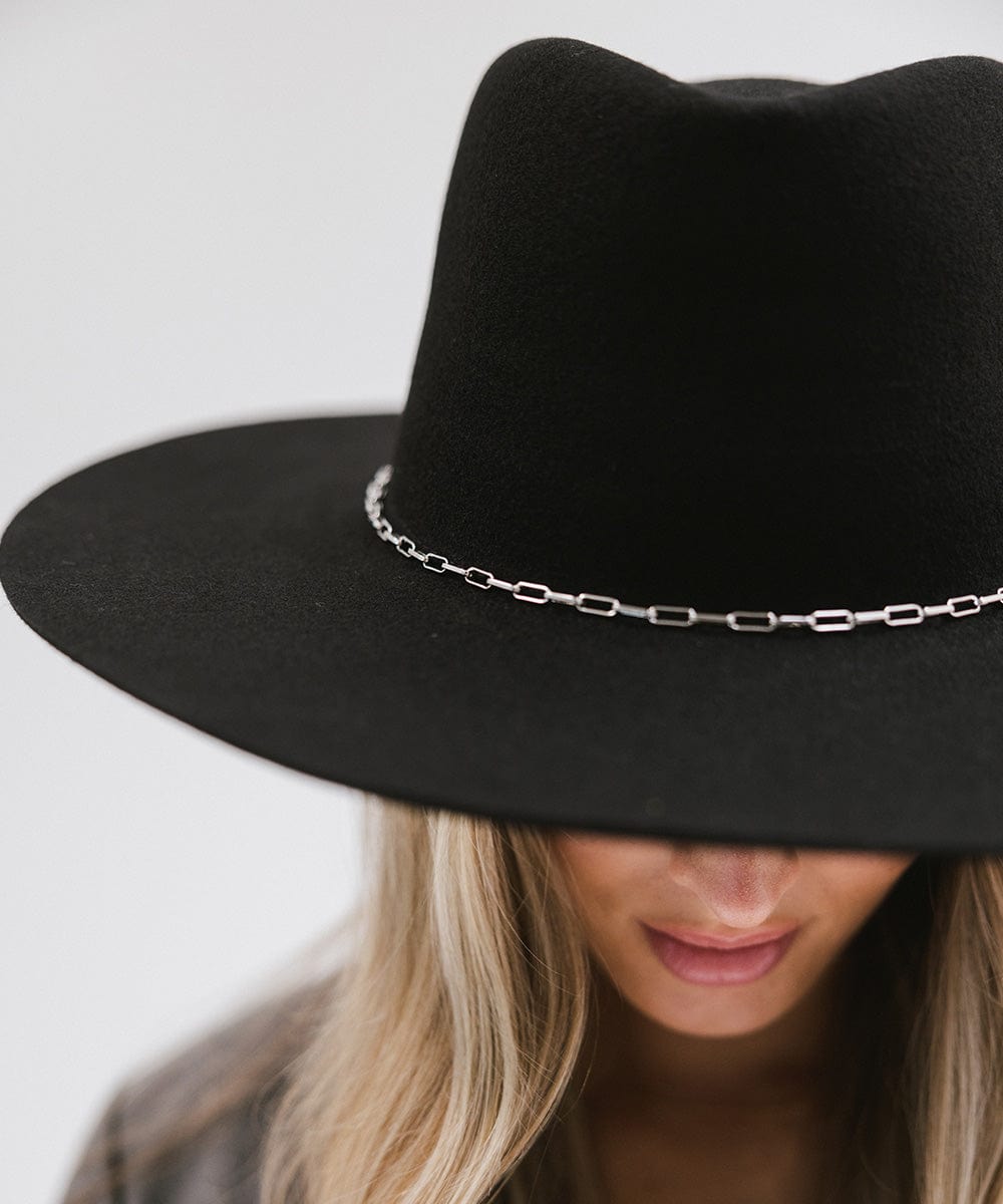 Woman wearing a black wide-brimmed hat with a silver paperclip chain hat band against a plain background #color_silver