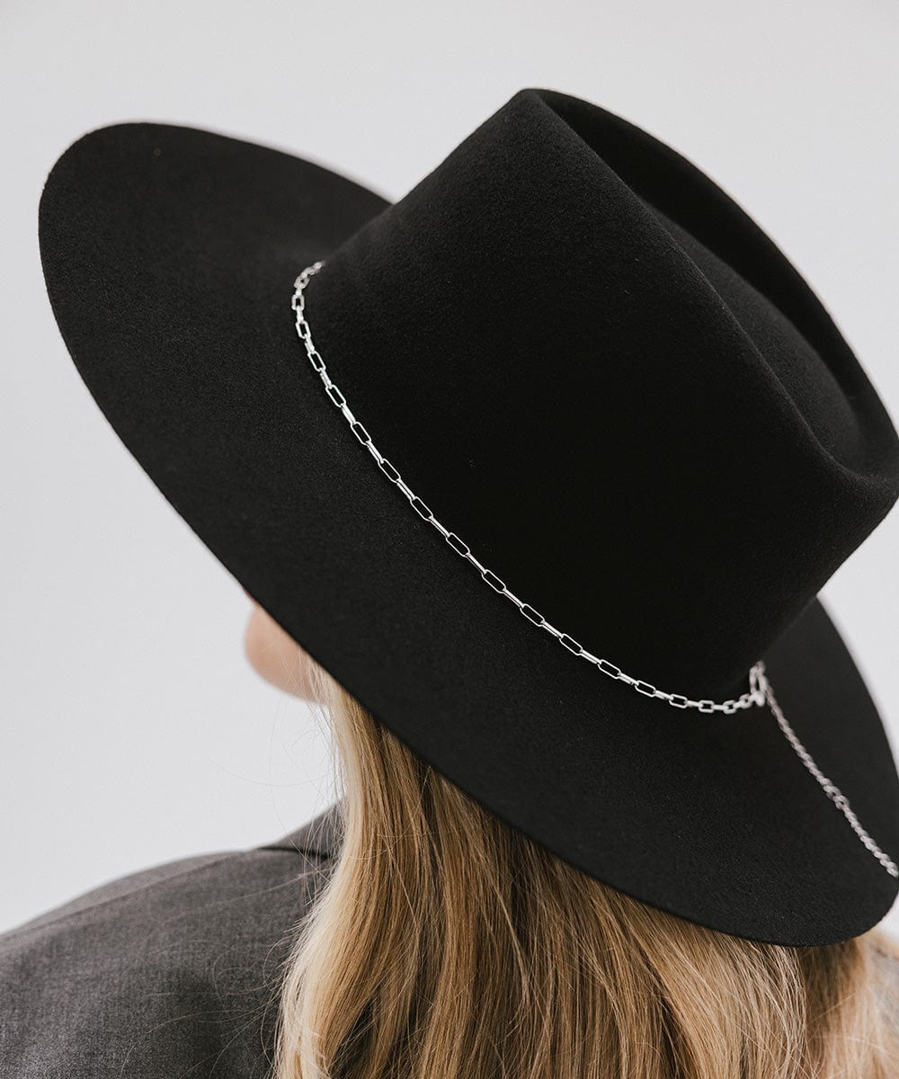Close up image of a woman wearing a black wide-brimmed hat with a silver paperclip chain hat band against a plain background #color_silver