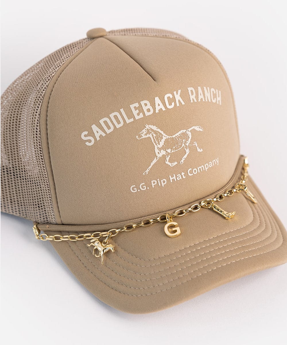 A beige cap with a horse logo and the text 'SADDLEBACK RANCH' and 'G.G. Pip Hat Company', with a gold trucker link chain band with hat charms on a plain background #color_gold