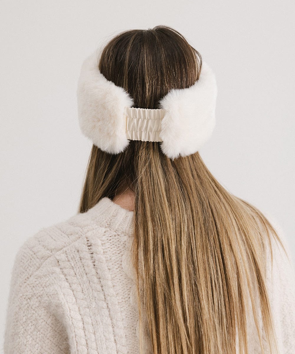 Woman with long hair wearing a winter white colored fur headband and a white sweater, facing behind against a plain background #color_winter white