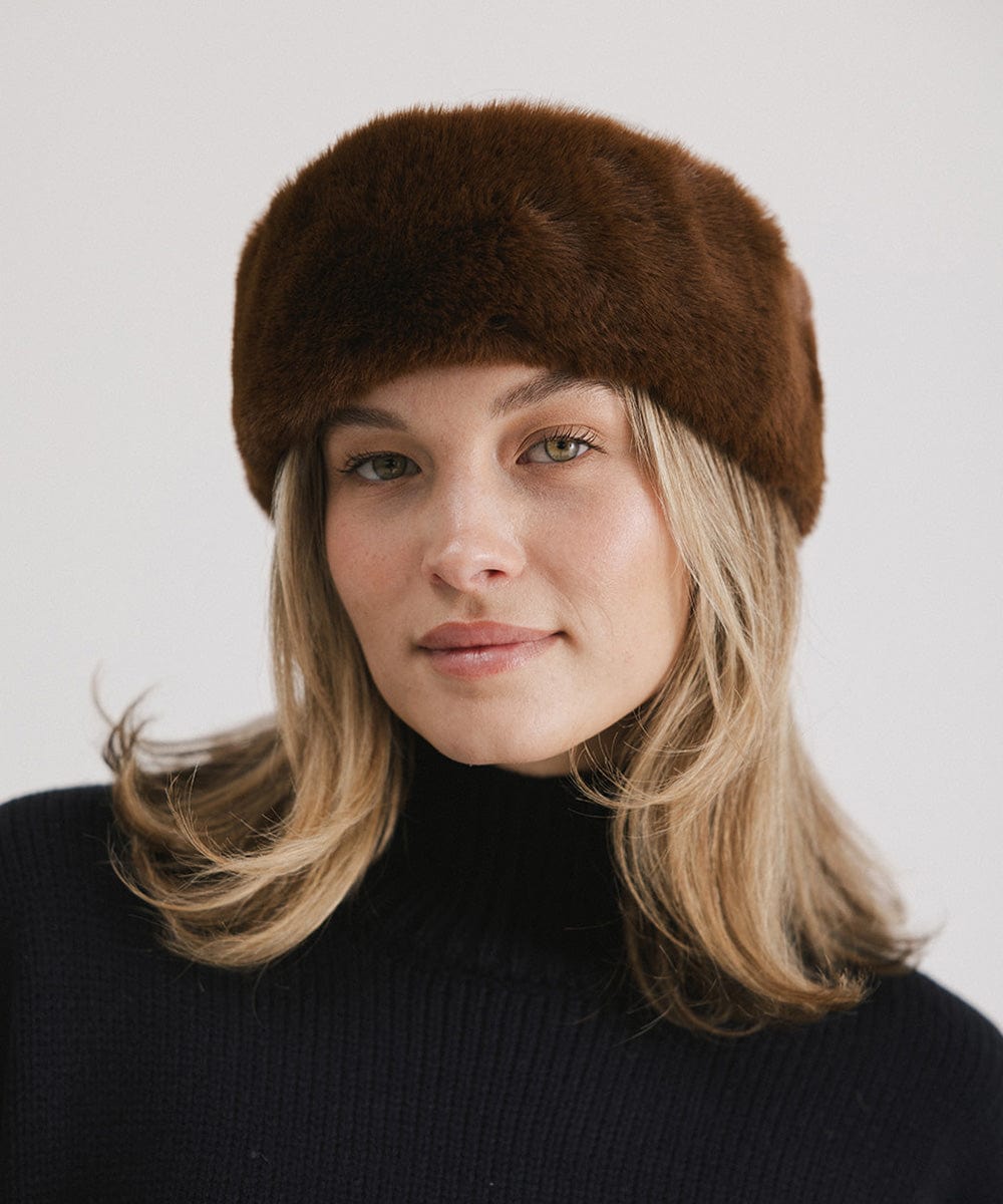 Woman wearing a brown fur headband and a black sweater against a plain background #color_brown