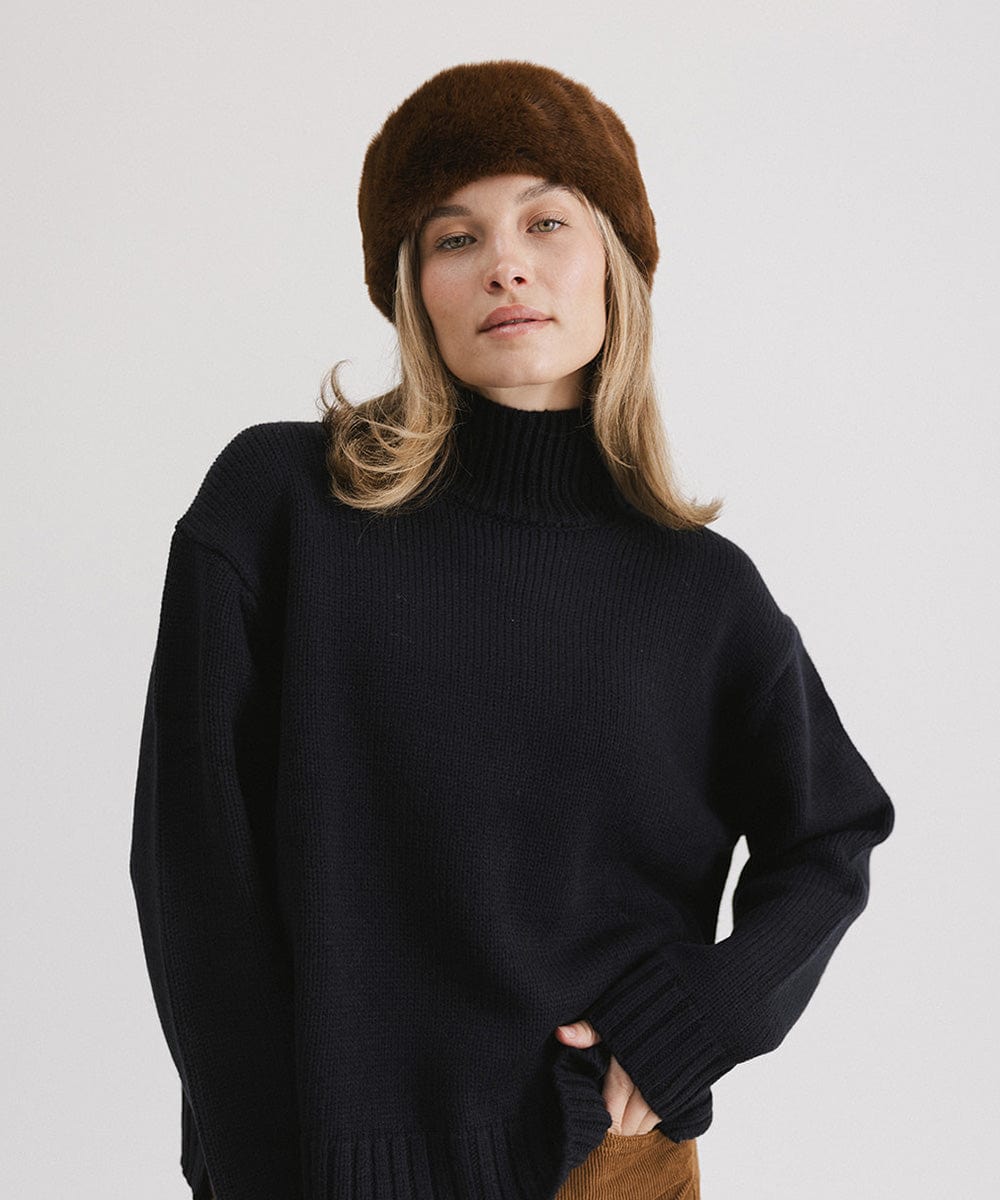 Woman wearing a brown fur headband and a black sweater, posing against a plain background #color_brown