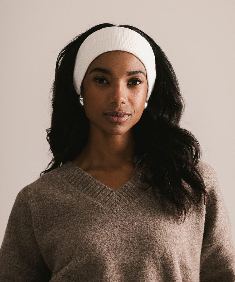 Woman wearing a white headband and brown sweater against a plain background #color_ivory