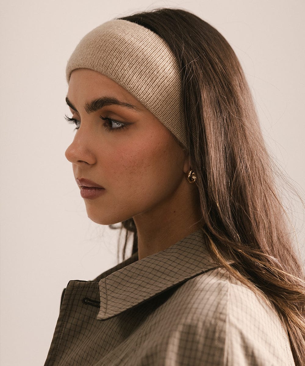 Woman wearing a beige knitted headband against a neutral background #color_tan