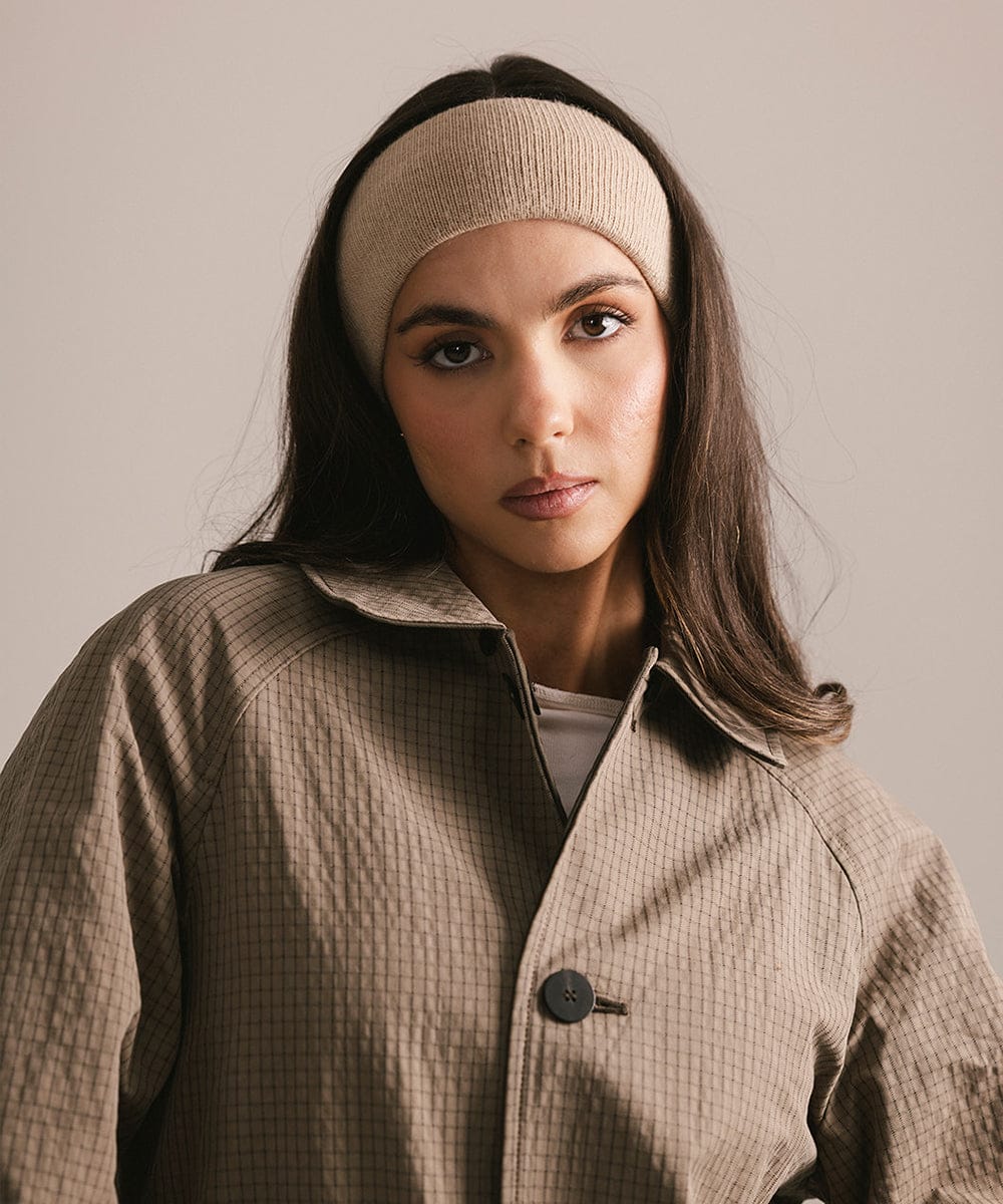 Woman wearing a beige headband and coat against a plain background #color_tan