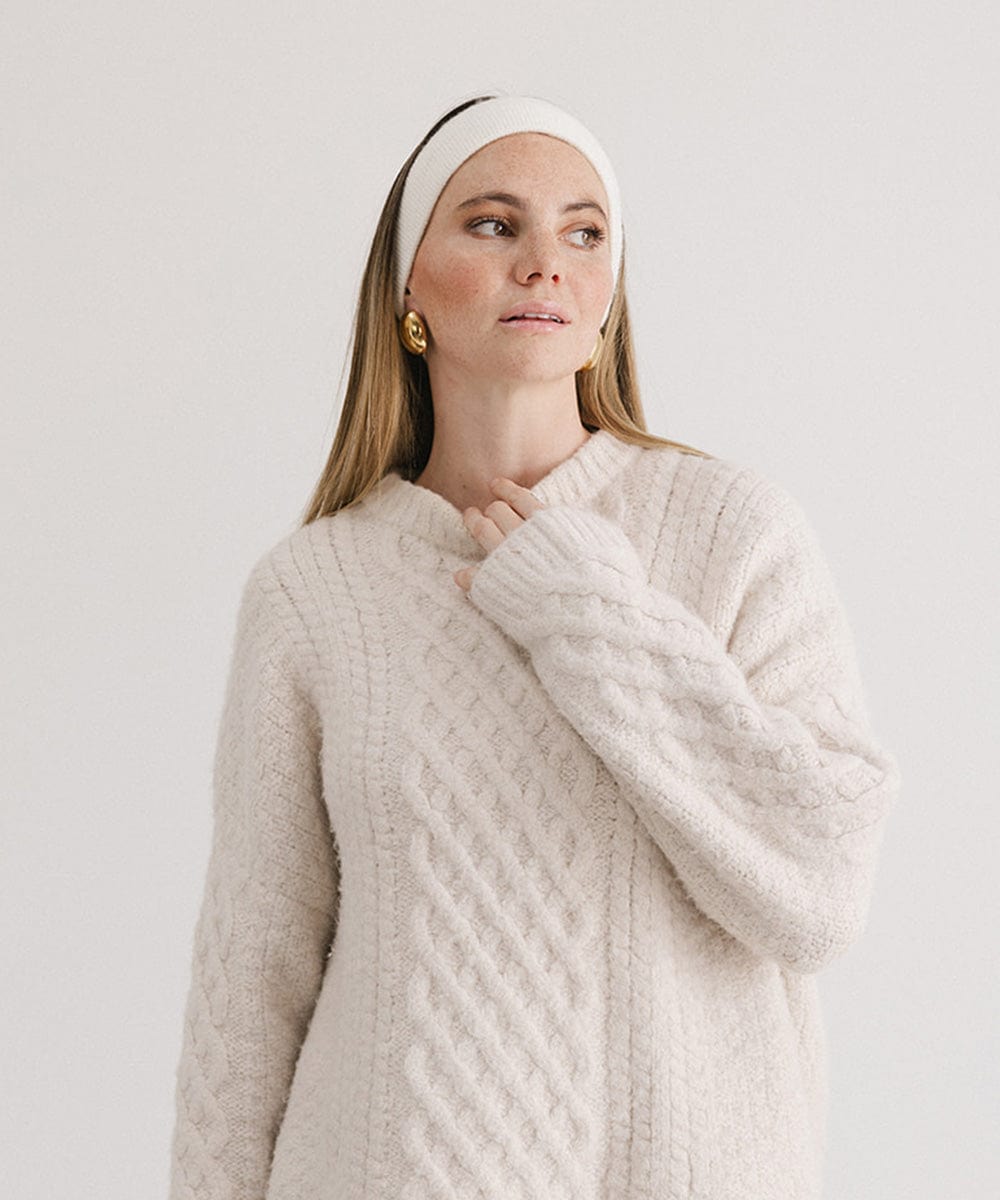 Woman wearing an ivory colored headband and a white sweater, posing against a plain background #color_ivory