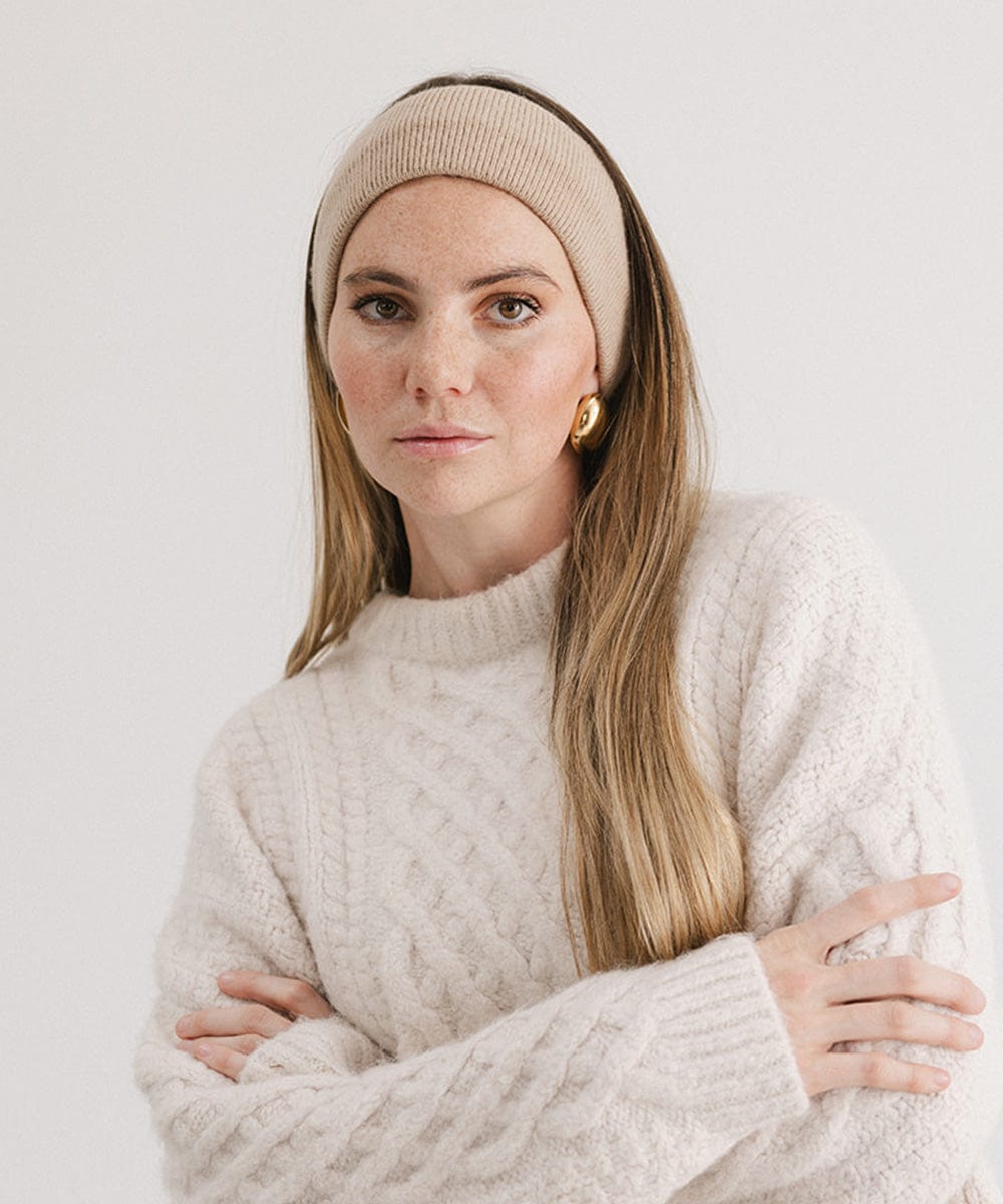 Woman wearing a tan headband and a white sweater against a plain background #color_tan