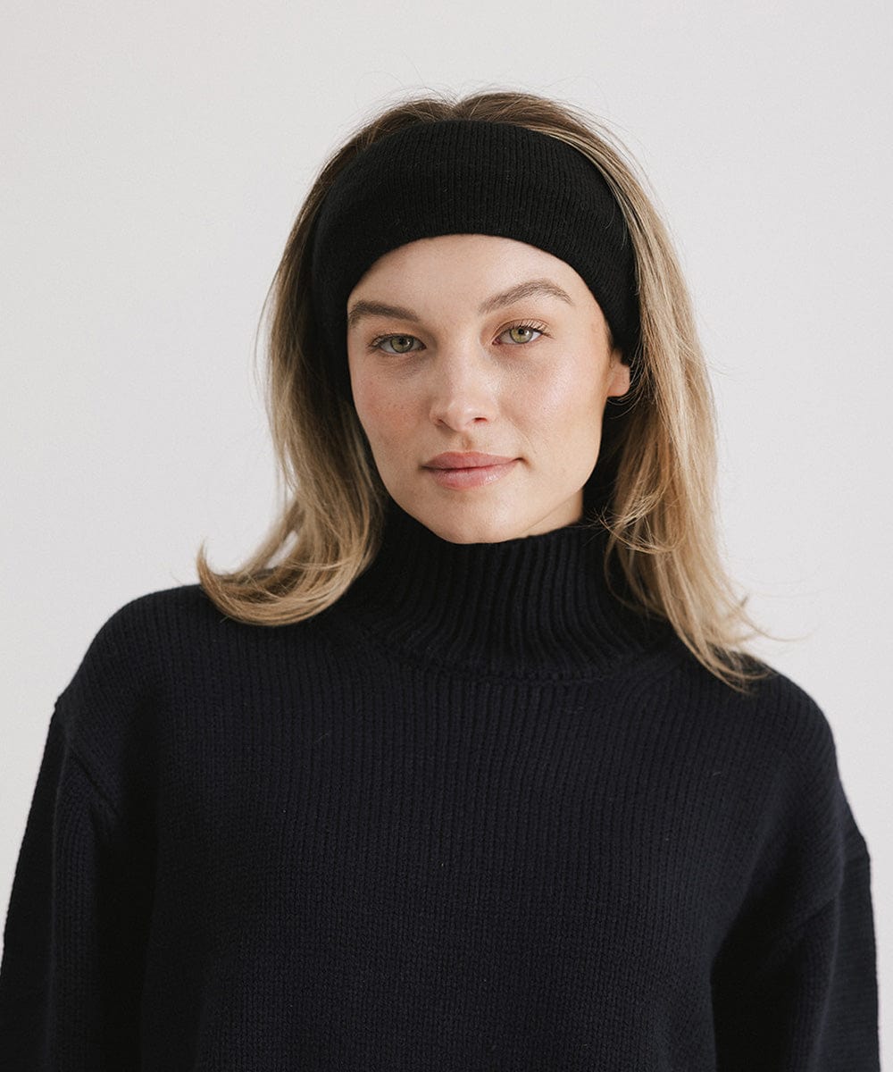 Woman wearing a black headband and a black sweater against a plain background #color_black