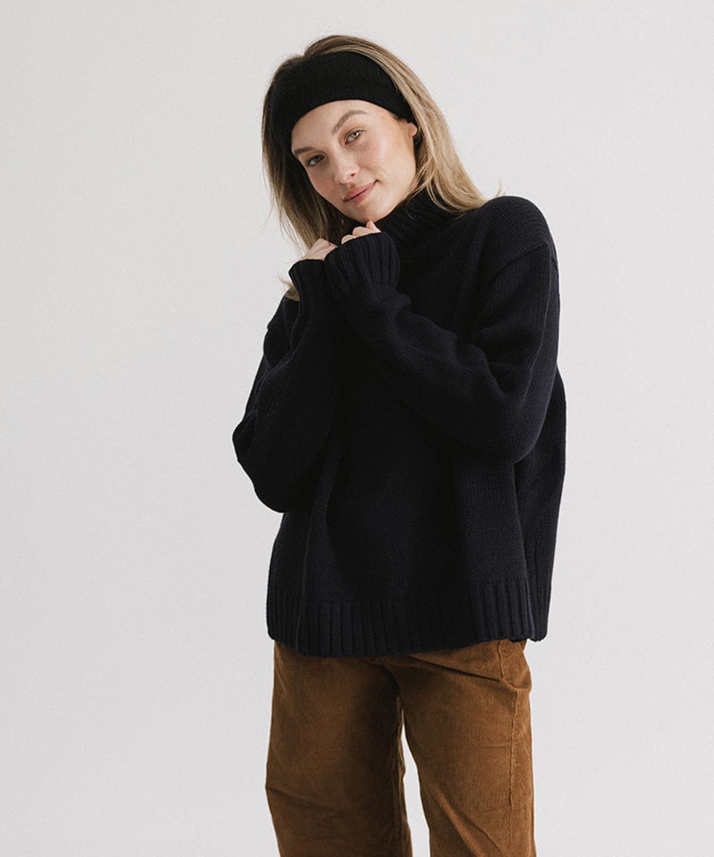 Woman wearing a black headband, a black sweater and brown pants against a plain background #color_black