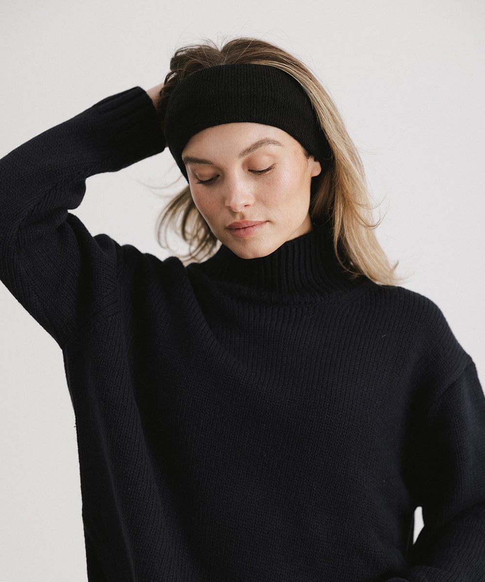Woman wearing a black headband and a black sweater, posing against a plain background #color_black