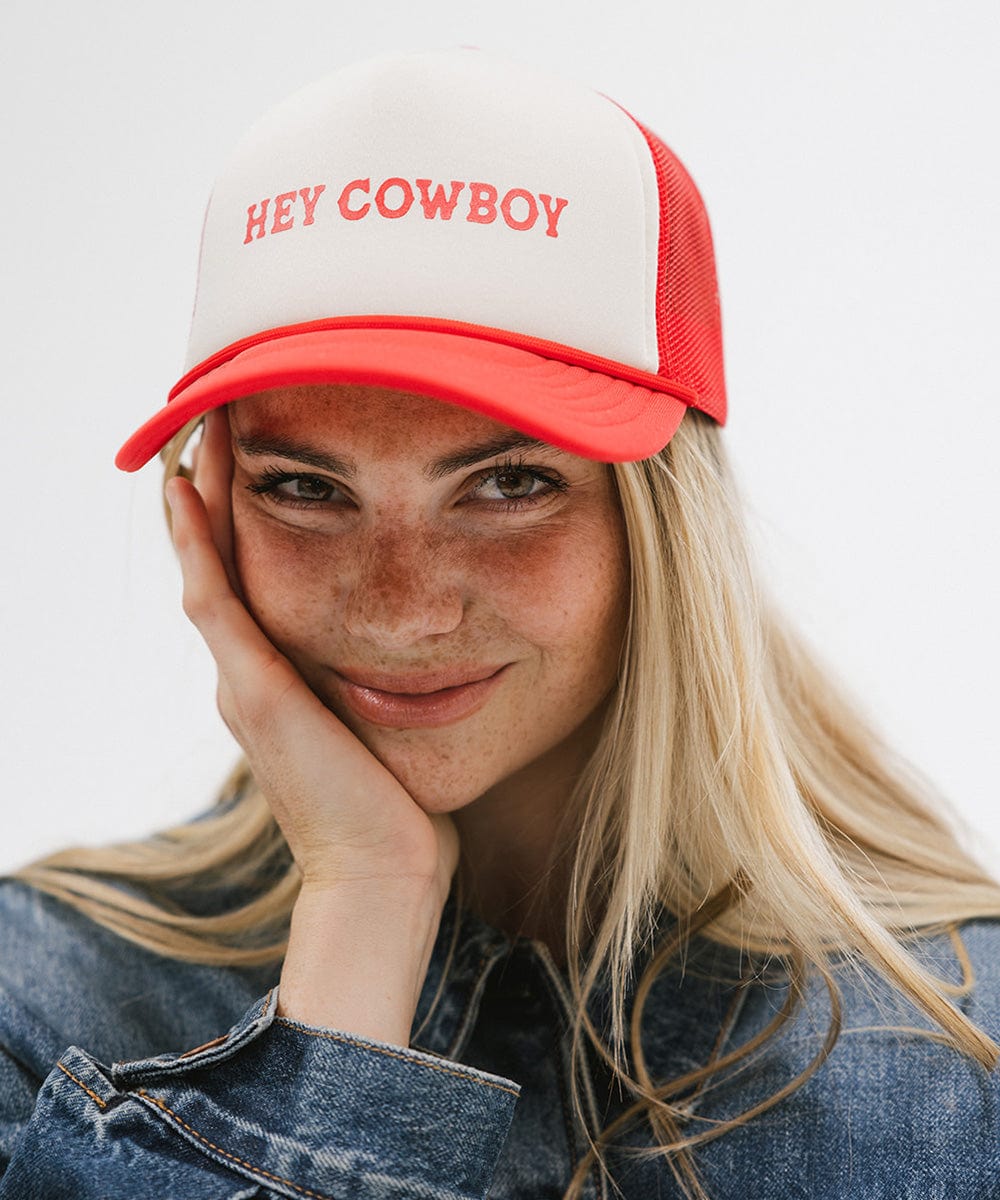 Woman wearing a cream and vintage red cap with 'Hey Cowboy' text and a denim shirt against a plain background #color_cream-vintage red