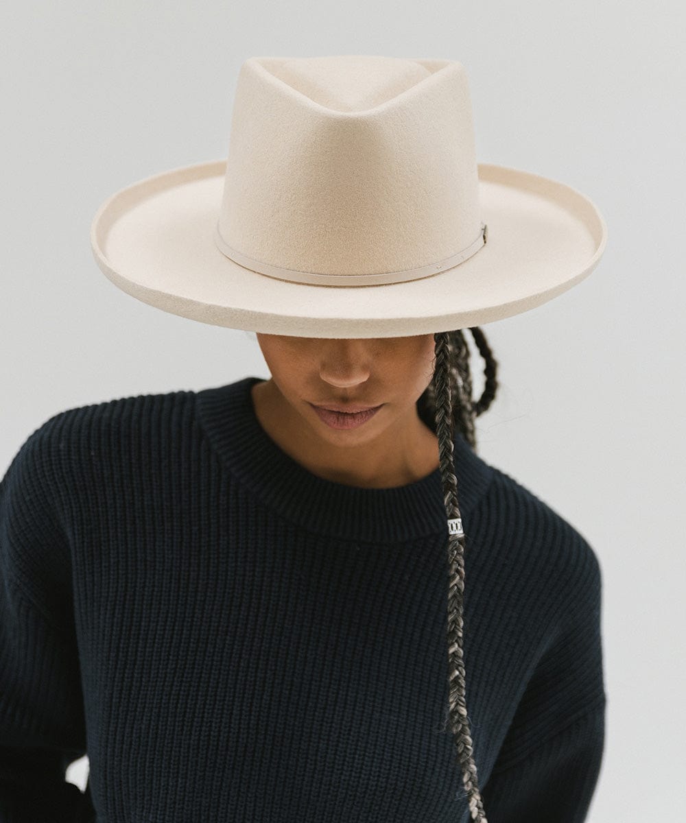 Person wearing a cream Lennon pencil brim fedora hat with a hat band and a blue sweater, posing against a plain background #color_cream