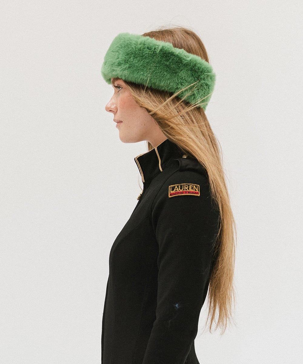 Woman wearing an evergreen colored fur headband and a black jacket, facing sideways against a plain background #color_evergreen