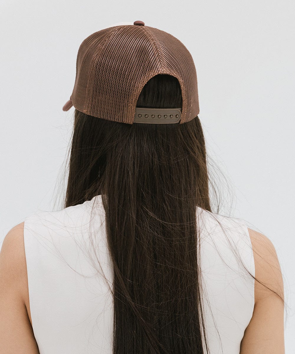 Woman wearing a brown cap and a white top against a plain background #color_cream - chocolate brown