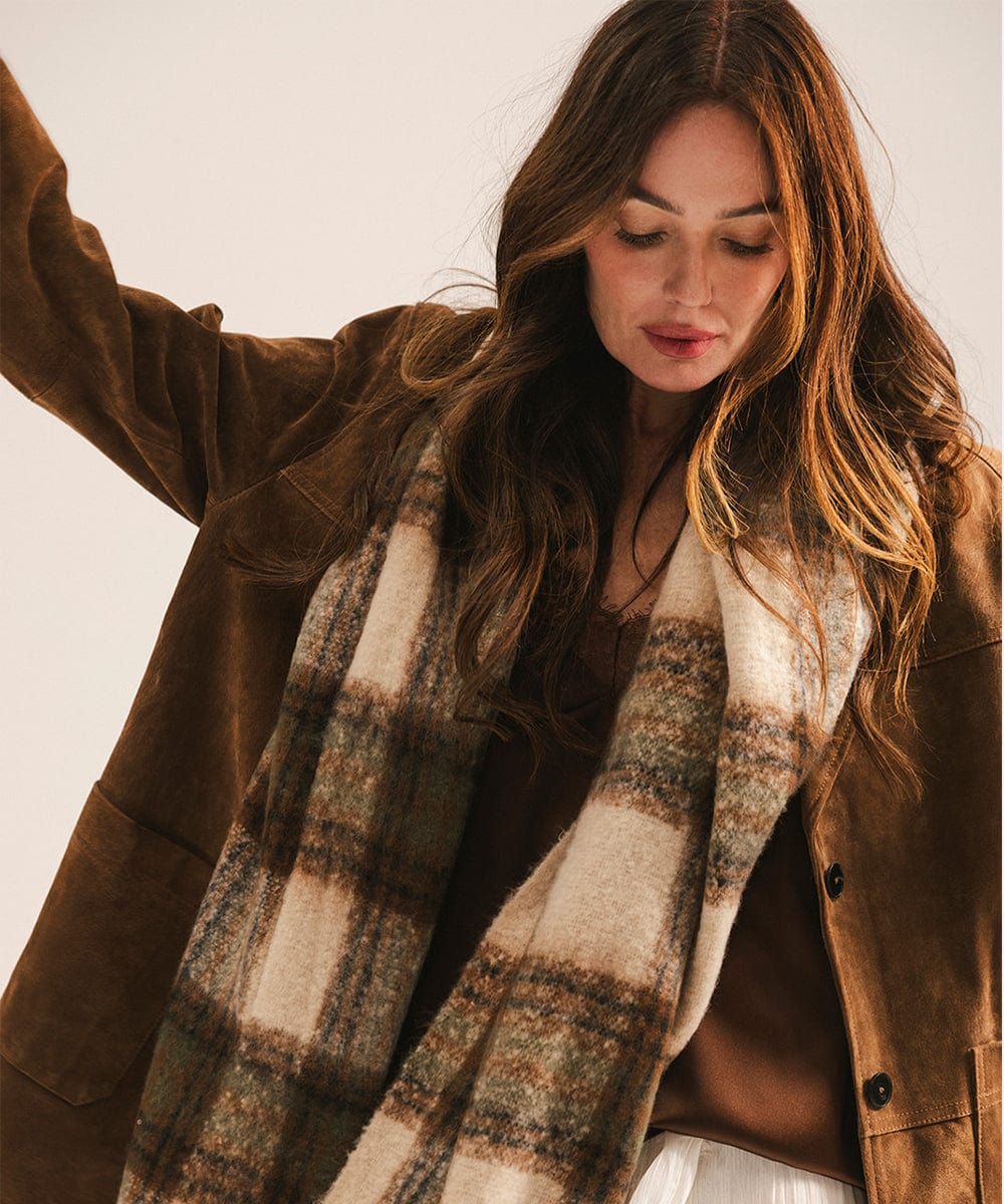 Woman wearing a brown coat and plaid scarf against a plain background #color_cream - tan