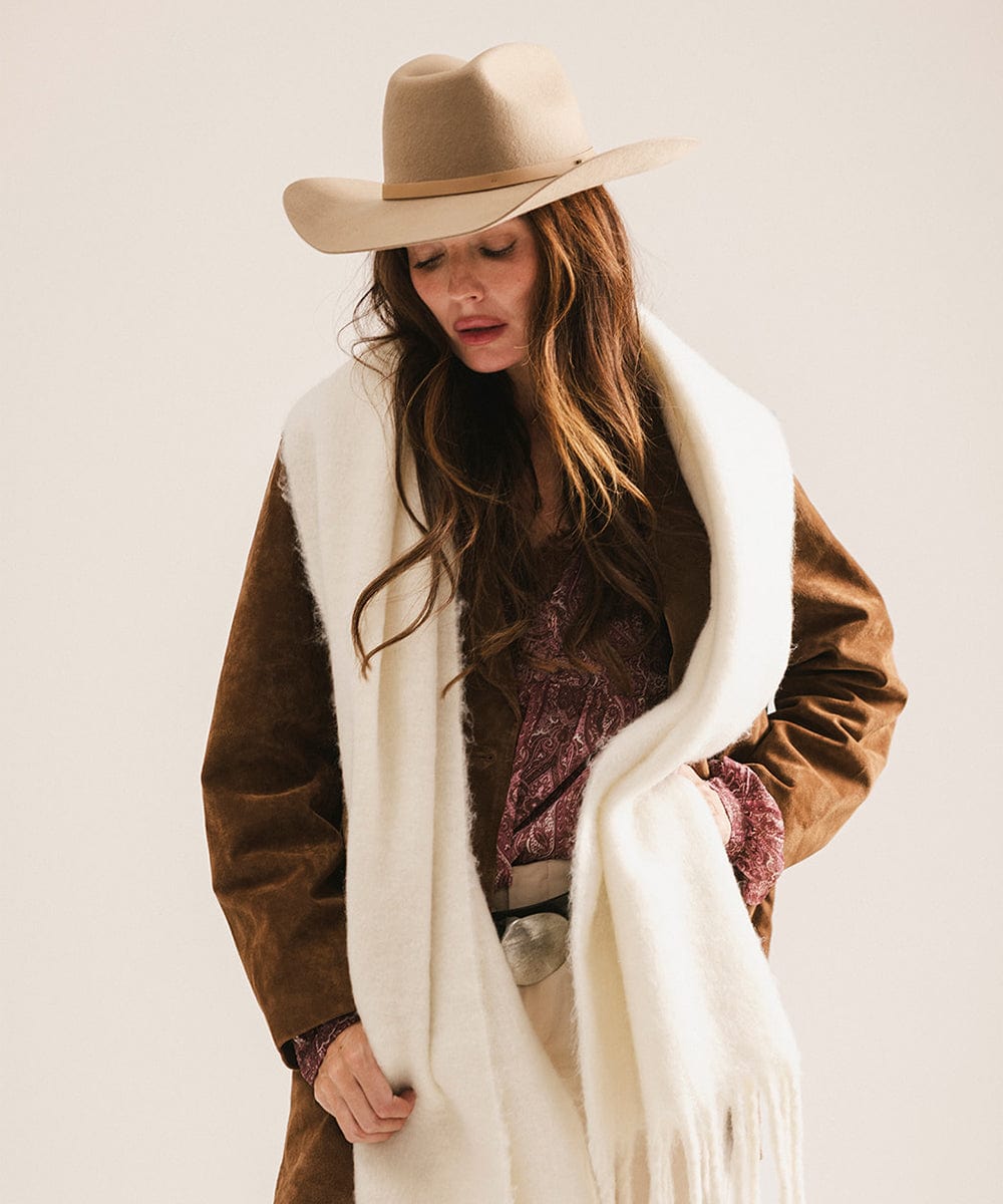 Woman wearing a brown coat, white scarf, and beige hat on a plain background #color_off white