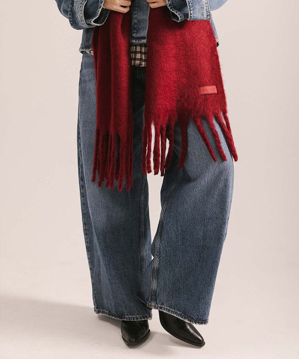 Person wearing a red scarf, denim jacket, and jeans on a beige background #color_burgundy