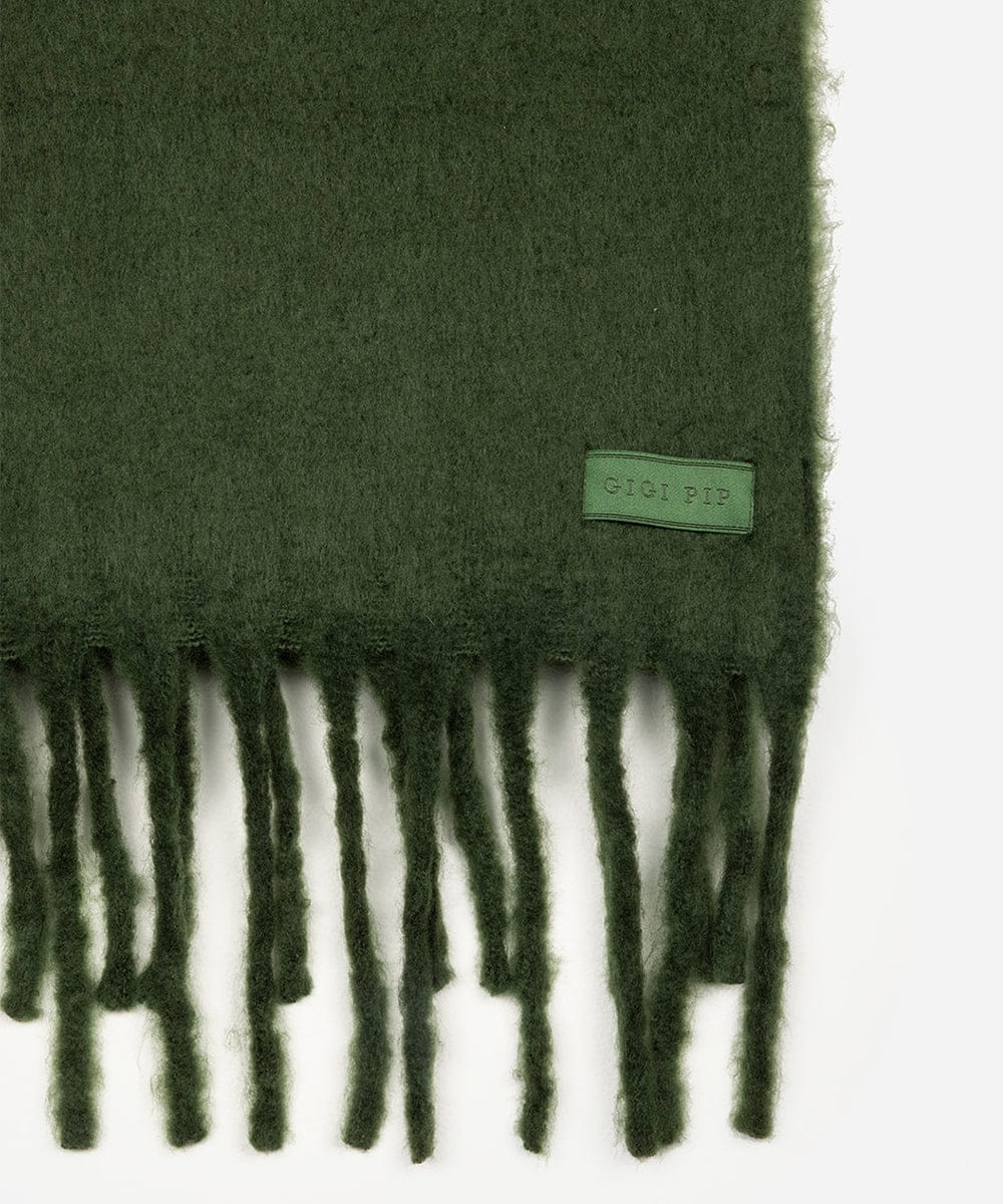 Green scarf with fringes and a brand label on a white background #color_dark green