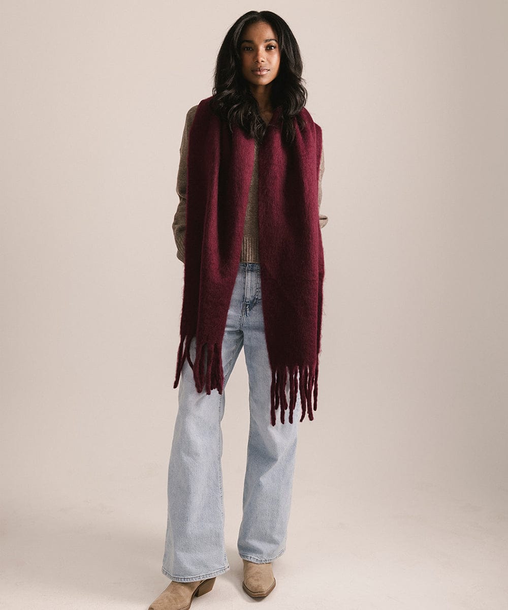 Woman wearing a burgundy scarf with tassels on a beige background #color_merlot