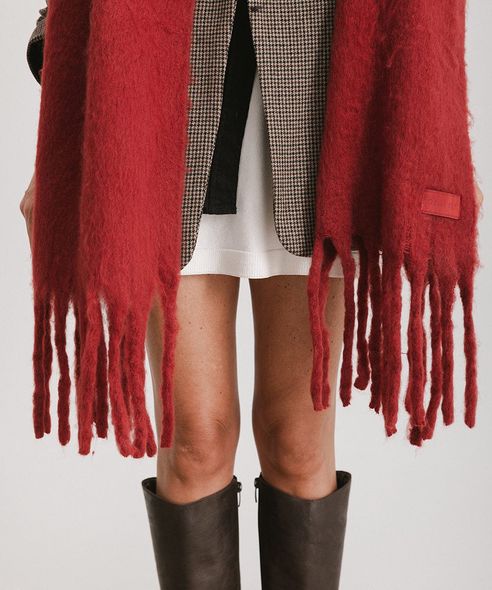 A burgundy oversized knit scarf with fringes, worn by a person against a plain background #color_burgundy
