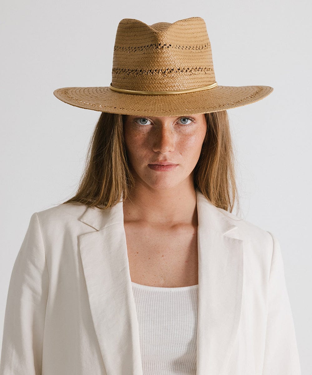 Woman wearing a honey colored teardrop straw fedora hat with a band and a white blazer against a plain background #color_honey