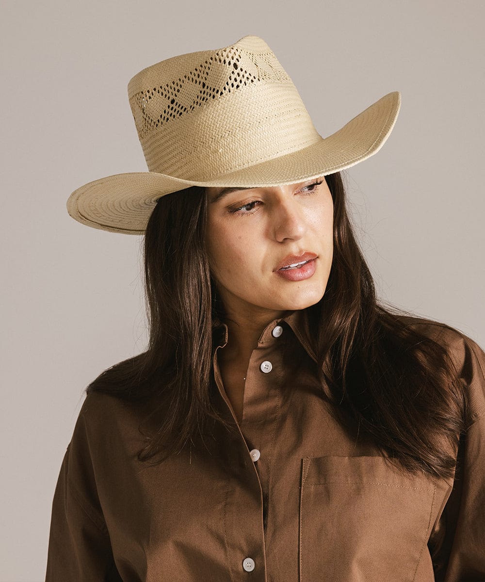 Woman wearing a natural colored straw hat and a brown shirt against a plain background #color_natural