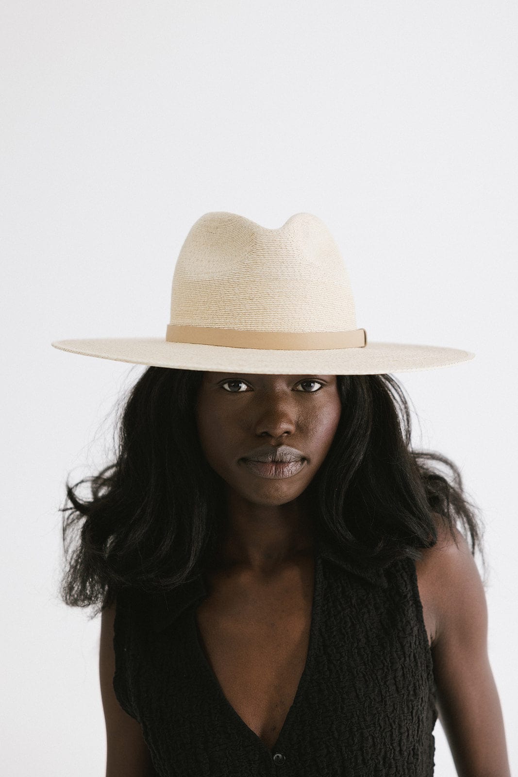 Woman wearing a natural colored Blake Wide Brim Fedora Hat with a hat band and a black top against a plain background #color_natural