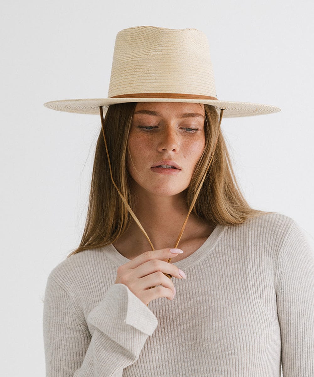 Woman wearing an ivory palm straw sun hat and a white t-shirt against a plain background #color_ivory