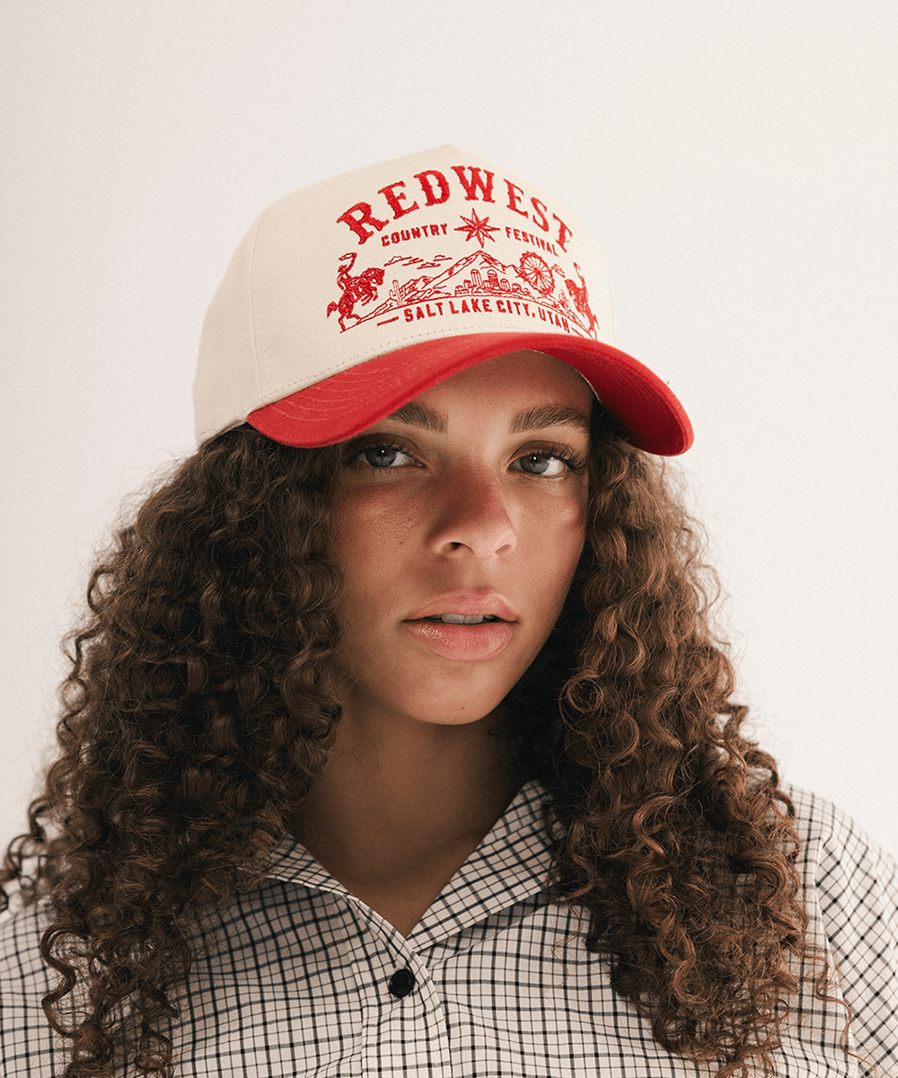 Woman wearing a red and white baseball cap and plaid shirt in a white background #color_cream - rust red