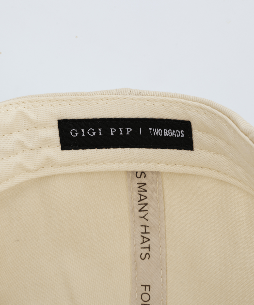 Embroidery inside a hat that says 'GIGI PIP | TWO ROADS' in a white background #color_cream - brown