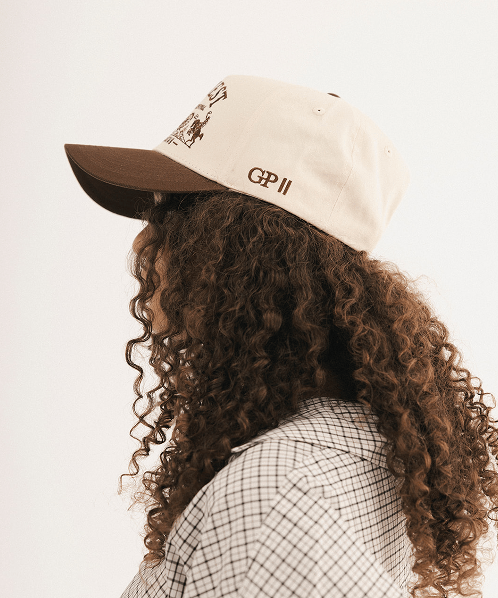 Woman's side view wearing a brown and white baseball cap and plaid shirt in a white background #color_cream - brown
