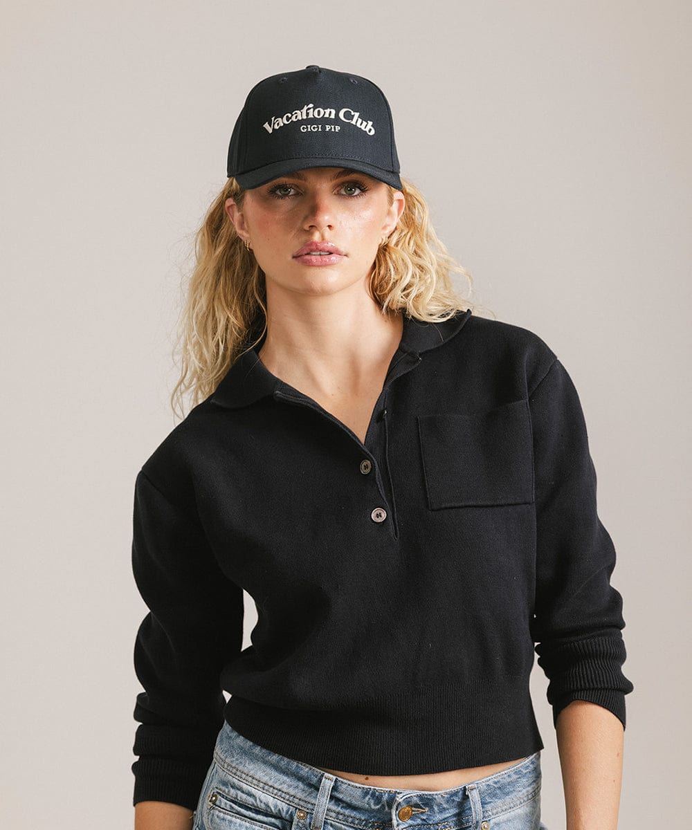Woman wearing a navy cap with 'Vacation Club' text and a black shirt against a plain background #color_navy