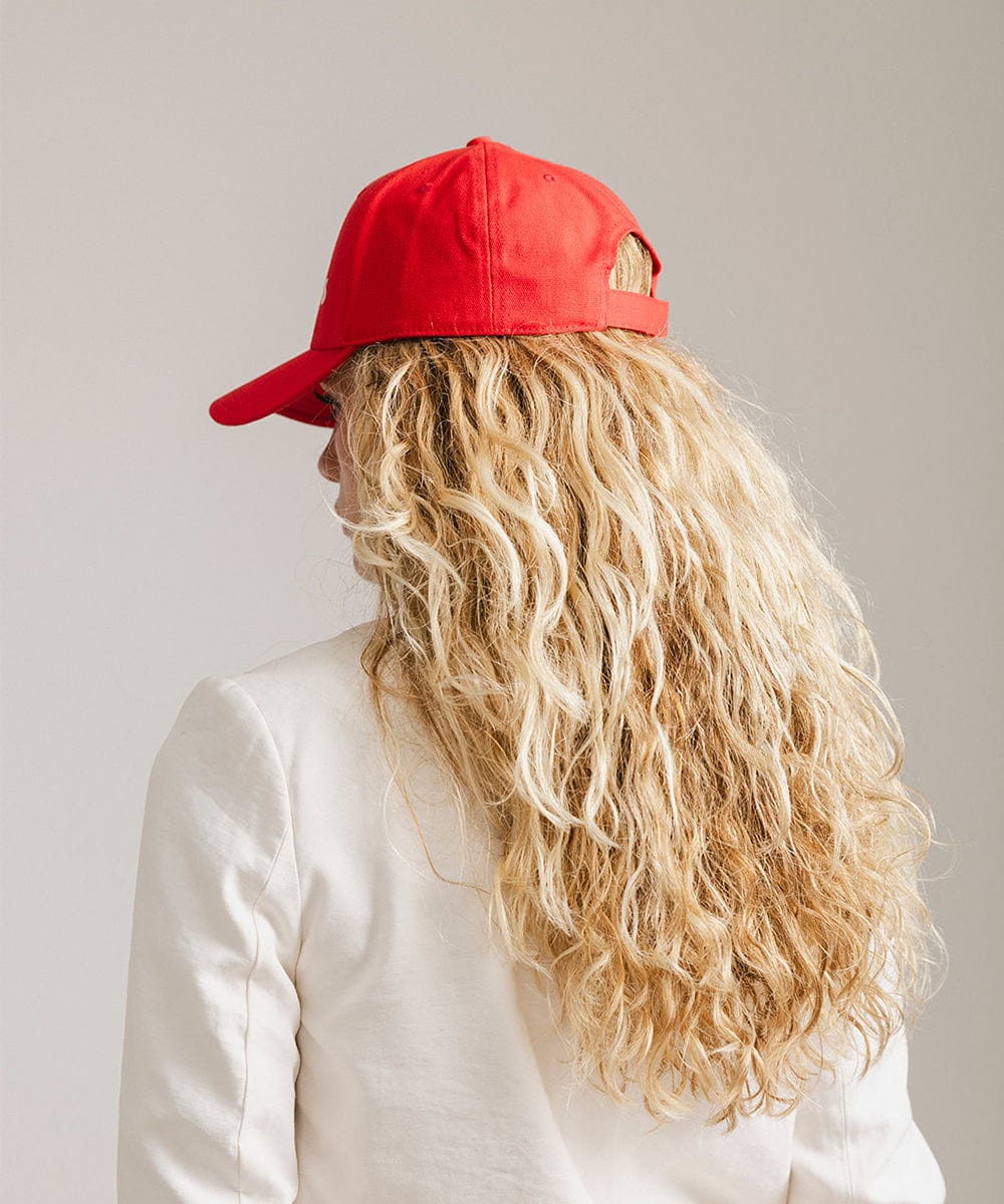 Woman wearing a red cap and a white coat against a plain background #color_red